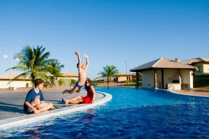 un grupo de personas sentadas en el borde de una piscina en Condomínio Encantador Piscina e Praia E12 en Zumbi