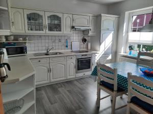 a kitchen with white cabinets and a table in it at Ferienhaus FRIESENNEST in Norden