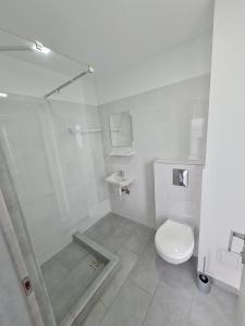 a white bathroom with a shower and a toilet at Waterman in Costinesti