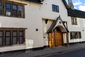 a white building with a wooden door on a street at Premiere City Centre Apartment with Gated Parking and Excellent Feedback, Big Double Bedroom, Balcony, Courtyard Garden, Ideal for Long Stays, WFH, Getaways and Ongoing Contracts in Peterborough