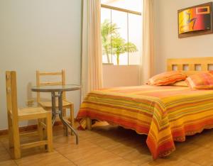 a bedroom with a bed and a table and a window at Takora Inn in Tacna