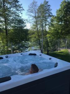 a person in a jacuzzi tub in a yard at Hotel Rezydencja Mazury SPA & Lake in Mrągowo