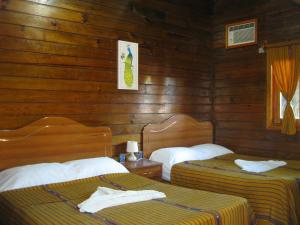 two beds in a room with wooden walls at Mar Marine Yacht Club in Rio Dulce