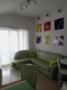 ein Wohnzimmer mit einer grünen Couch und Gemälden an der Wand in der Unterkunft Apartman Thorsten in Malinska