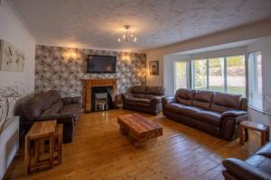 sala de estar con muebles de cuero y chimenea en Gleneden House, en Tore