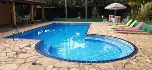 a large blue swimming pool with chairs and an umbrella at Chácara em Araçoiaba da Serra in Araçoiaba da Serra +39 photos