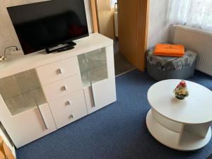 a room with a tv and a white dresser with a table at Ferienwohnung Wede in Ueckeritz