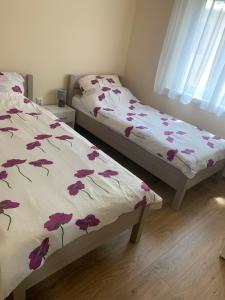 ein Schlafzimmer mit 2 Betten mit Blumen auf der Bettwäsche in der Unterkunft Alexa apartman in Hajdúszoboszló