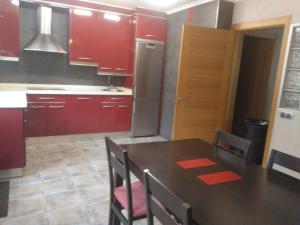 a kitchen with red cabinets and a table with chairs at Casa Pimen in Gijón