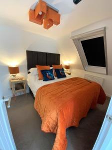 een slaapkamer met een bed met een oranje dekbed en een raam bij THE HIDEAWAY - LUXURY SELF CATERING COASTAL APARTMENT with PRIVATE ENTRANCE & KEY BOX ENTRY JUST A FEW MINUTES WALK TO THE BEACH, SOLENT WAY WALK, SHOPS and many EATERIES & BARS - FREE OFF ROAD PARKING,FULL KITCHEN, LOUNGE,BEDROOM , BATHROOM & WI-FI in Lymington