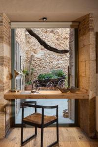 una mesa con una silla frente a una ventana en Domus Renier Boutique Hotel en La Canea