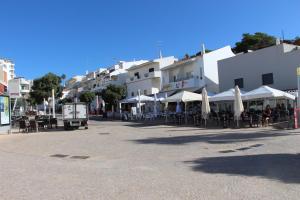 a street with tables and chairs and umbrellas and buildings at Ocean and pool in Olhos de Água