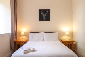 sypialnia z białym łóżkiem i 2 szafkami nocnymi w obiekcie Fantastic Cottage in Loch Lomond National Park w mieście Alexandria