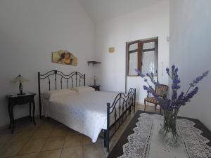 1 dormitorio con 1 cama y un jarrón con flores púrpuras en Azienda Agrituristica Masseria La Verna, en Patù