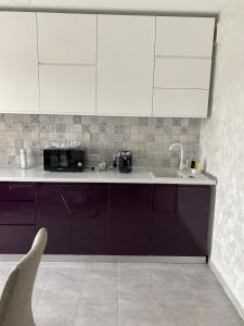 a kitchen with purple and white cabinets and a sink at Dina Lux Iasi Apartment in Iaşi +46 photos