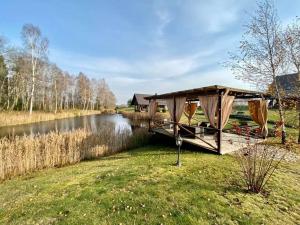 a boat with a canopy on the side of a river at Stonkų sodyba Grapeldvaris in Varkaliai