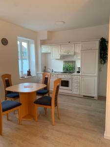a kitchen with white cabinets and a table and chairs at Ferienwohnung 2 Zimmer 55 qm Betten trennbar 1 Stock in Ilbenstadt