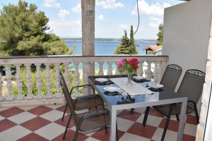 a table with a vase of flowers on a balcony at Beachfront - Vali in Tkon