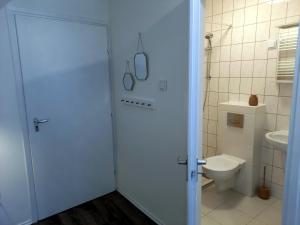 a white bathroom with a toilet and a door at Diókert Vendégház Sopron in Sopron