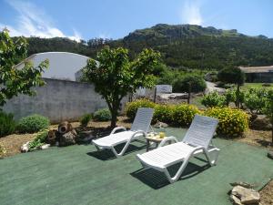 dos sillas blancas y una mesa en el césped en Casa Do Avô In Montejunto, en Cadaval