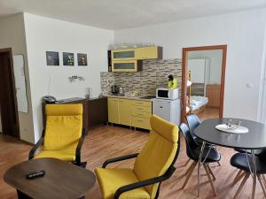 una cocina con mesa, sillas amarillas, mesa y sillón en Apartmanovy Dom Triangel, en Donovaly