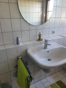 Baño blanco con lavabo y espejo en Ferienwohnung im Schwarzwaldhaus, en Behla