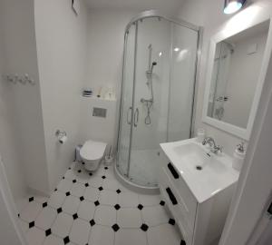 een witte badkamer met een douche en een wastafel bij Sunset II in Dziwnówek