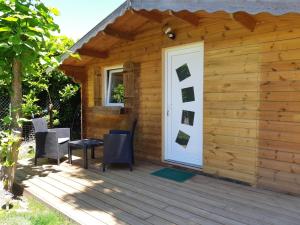 Cette cabane en bois est dotée d'une porte et de chaises blanches. dans l'établissement Logement proche Lyon-aéroport-Centrale Bugey, à Dagneux