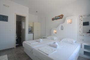 a white bedroom with two beds with towels on them at ThalaSEA - village Antiparos in Antiparos