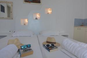 a white room with a bed with a hat and sunglasses at ThalaSEA - village Antiparos in Antiparos