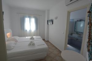 a white room with a bed and a mirror at ThalaSEA - village Antiparos in Antiparos