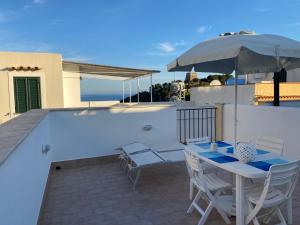 een patio met een tafel en stoelen en een parasol bij La Casetta di Ninetta in Ustica