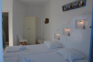 a white bedroom with two beds and a chair at ThalaSEA - village Antiparos in Antiparos
