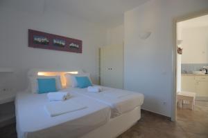 a bedroom with a large white bed with blue pillows at ThalaSEA - village Antiparos in Antiparos