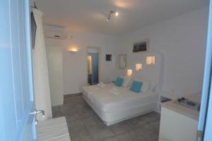 a white living room with a white couch and blue pillows at ThalaSEA - village Antiparos in Antiparos