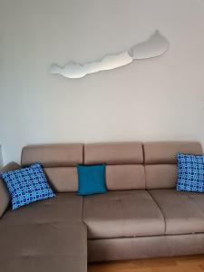 un divano marrone con cuscini bianchi e blu di EDA Beach Apartman a Siófok