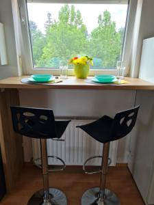 a kitchen counter with two chairs and a window at EDA Beach Apartman in Siófok