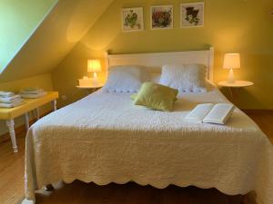 a bedroom with a white bed with two books on it at Le Clos Près Chambord in Maslives