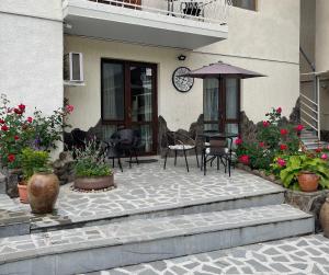 un patio con mesa, sombrilla y flores en Borjomi Apartments Apart Hotel en Borjomi