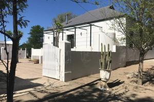 a white house with a fence and a cactus at House No1 in Nieu-Bethesda