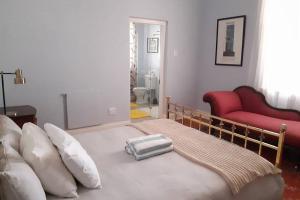 a bedroom with a bed with pillows and a red couch at House No1 in Nieu-Bethesda