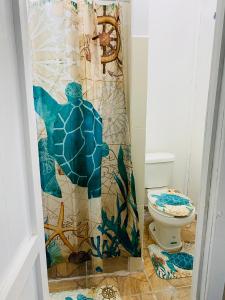 ein Badezimmer mit einem Duschvorhang neben einer Toilette in der Unterkunft Blue Sky Rentals Utila in Utila