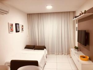 a white room with two beds and a tv at Iloa Apartamento Lindo in Barra de São Miguel