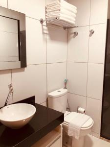 a bathroom with a toilet and a sink and a mirror at Iloa Apartamento Lindo in Barra de São Miguel