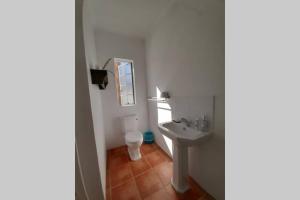 a white bathroom with a toilet and a sink at Snug Cottage in Nieu-Bethesda