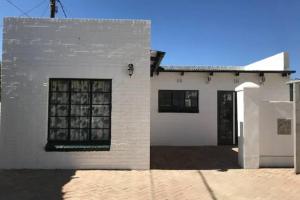 a white brick building with a black door at Snug Cottage in Nieu-Bethesda