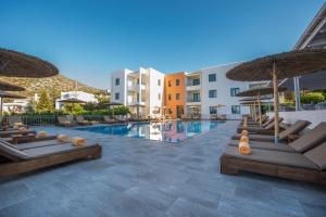 a pool with lounge chairs and umbrellas at a resort at Mitos Village in Hersonissos