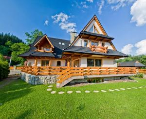 ein großes Holzhaus mit einem grünen Hof in der Unterkunft Leśny Dworek Zakopane in Zakopane