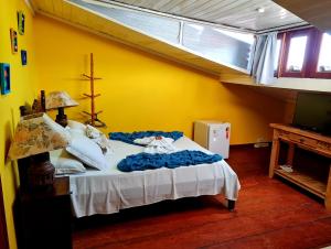 um quarto com uma cama num quarto amarelo em Pousada Talismã em Paraty