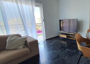 een woonkamer met een bank en een flatscreen-tv bij Rodos Beach Apartment 33 in Rhodos-stad